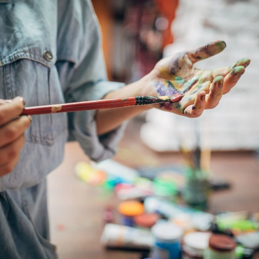 harmful myths about artists image of an artist with paint brush and paint on her hands