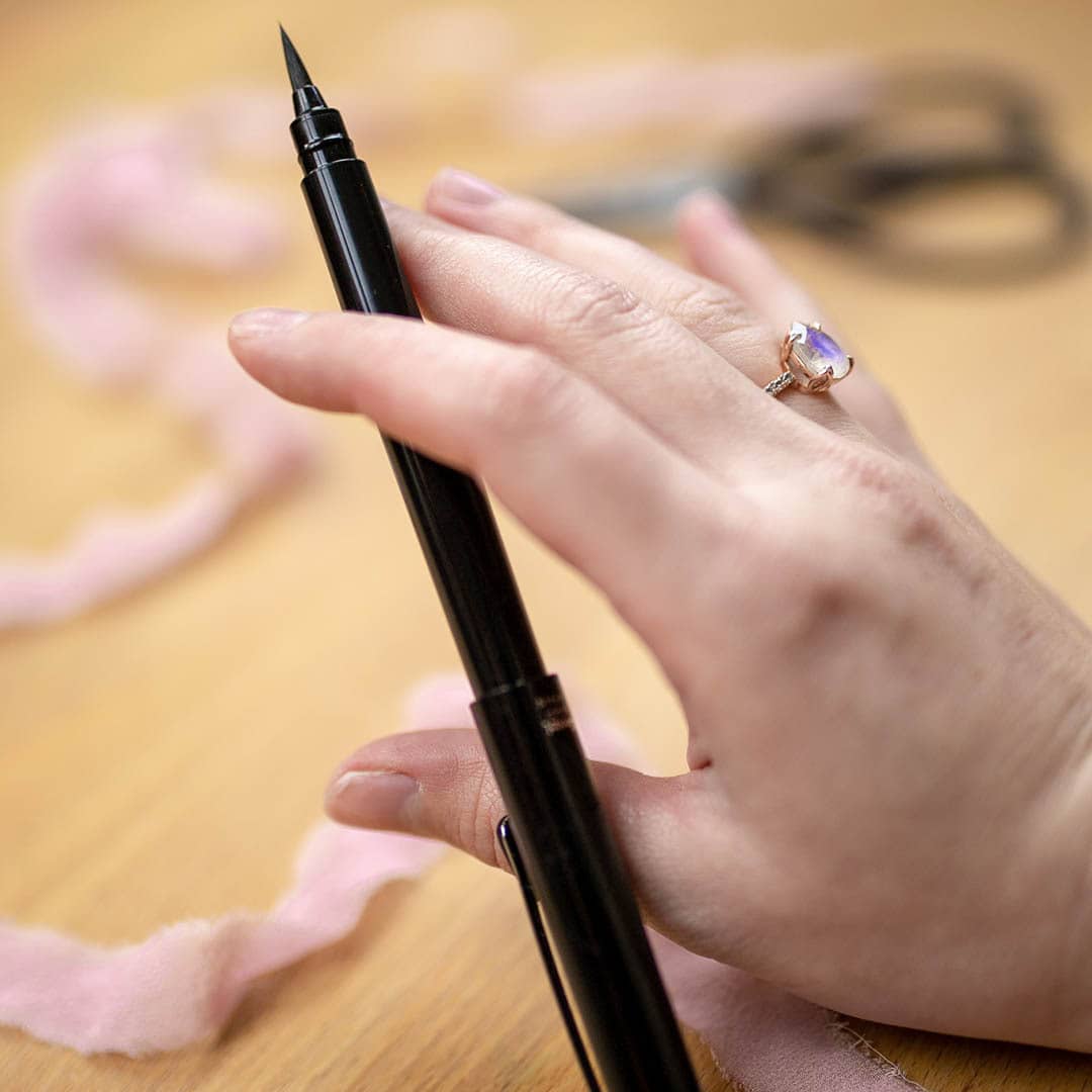 A woman's hand holding a Pentel Pocket Brush Pen.