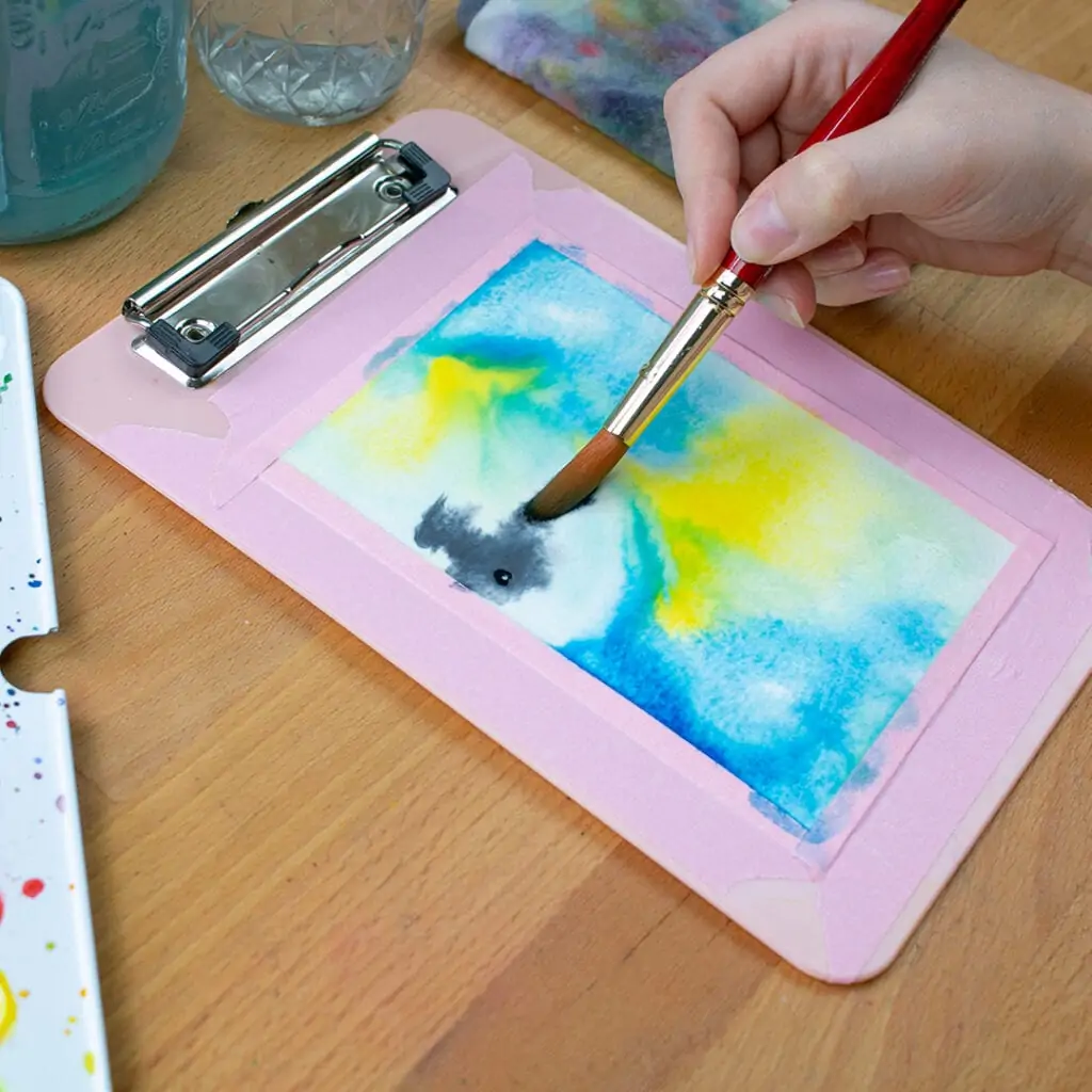 Small clipboard with watercolor painting in progress.