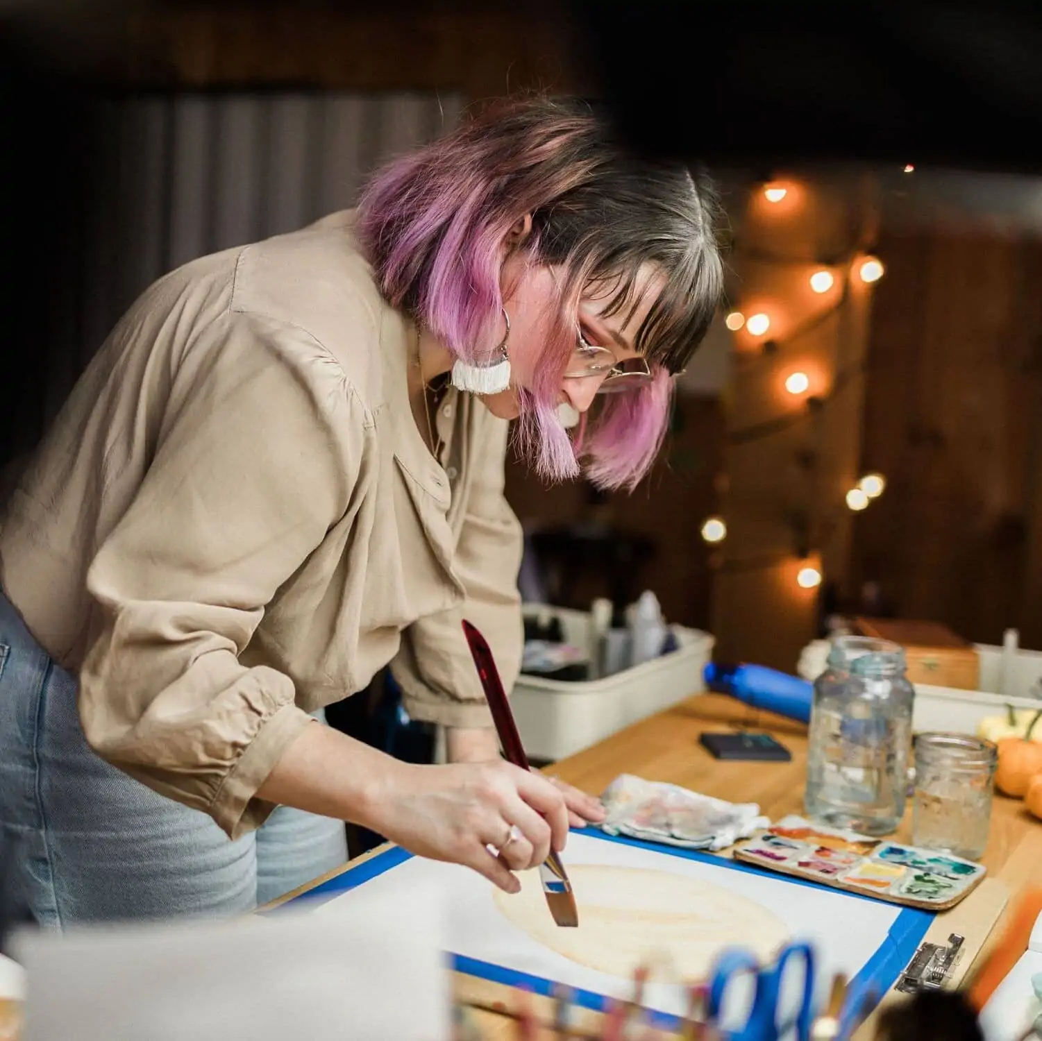 Image of Shelby standing at desk painting large circles.