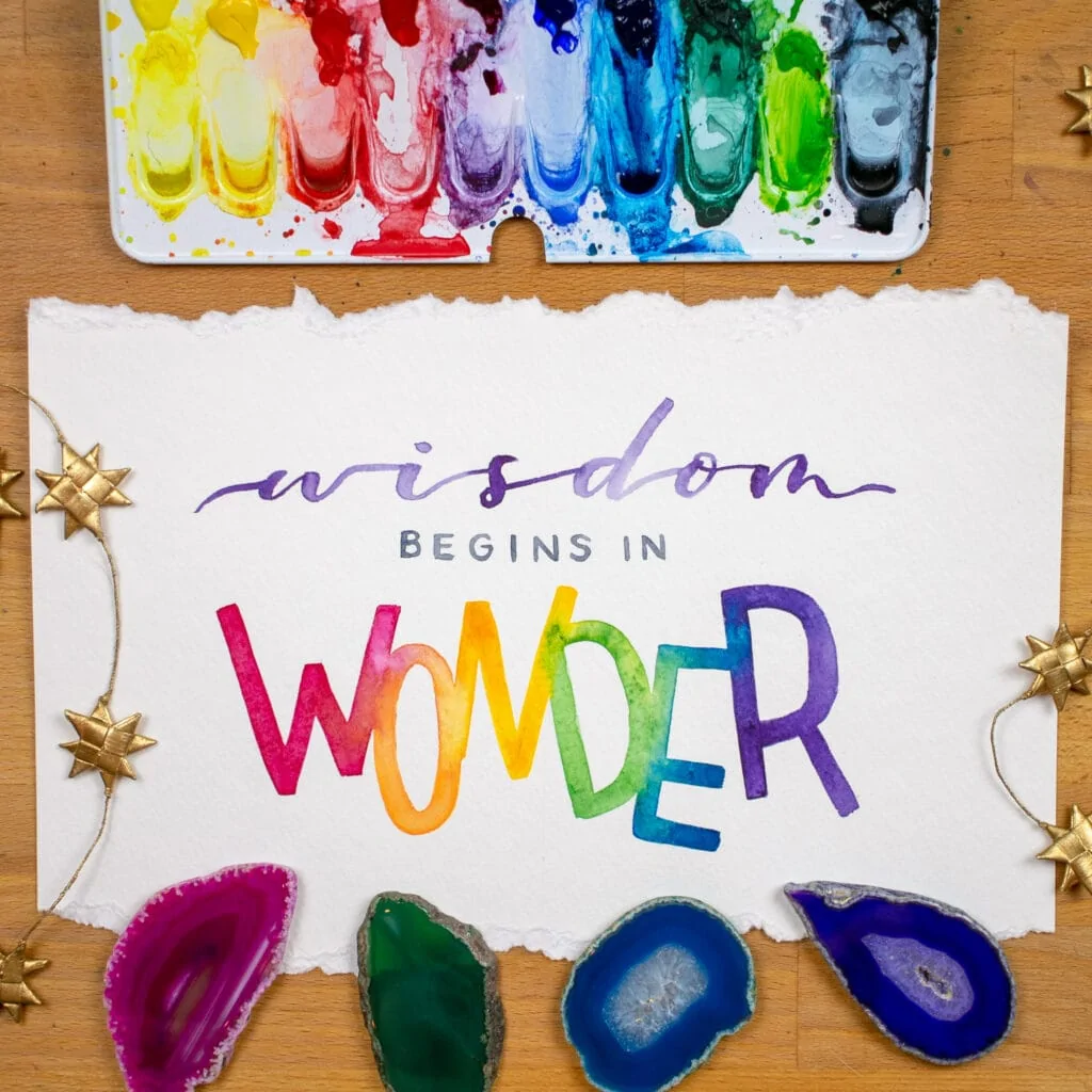 Watercolor lettered word "wonder" with rainbow colors.