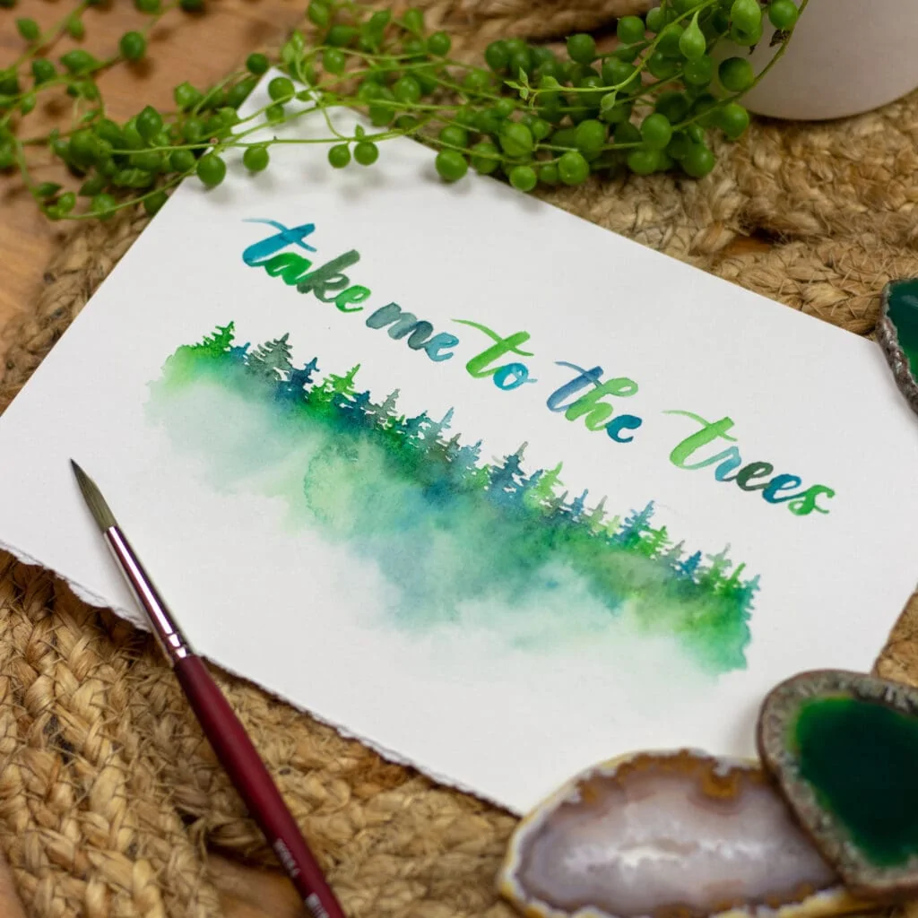 Watercolor lettered phrase reading "take me to the trees" with painted evergreens below.